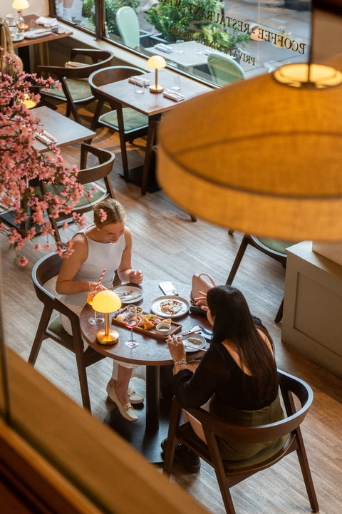 Two women dining at a restaurant with a warm, inviting atmosphere.